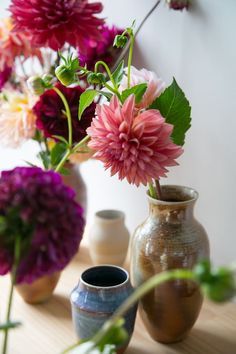 several vases with flowers in them sitting on a table next to eachother