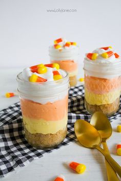 two jars filled with candy corn and marshmallows on top of a checkered table cloth