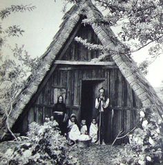 an old black and white photo of people in front of a hut