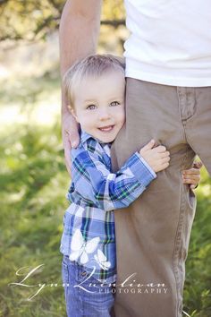 a little boy is holding his father's arm while he smiles at the camera