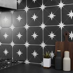 a black and white tiled kitchen with stars on the backsplash, potted plant and cutting board