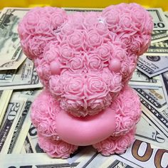 a pink teddy bear sitting on top of money