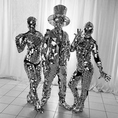 black and white photograph of three people made out of disco - themed material, standing in front of a curtain