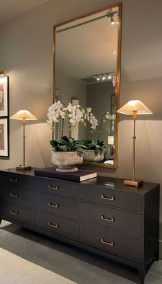 a large mirror sitting on top of a dresser next to a vase filled with flowers