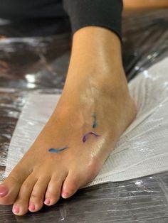 a woman's foot with a blue and purple tattoo on her left leg, sitting on plastic