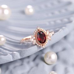 a close up view of a ring with pearls on it and an oval shaped red stone surrounded by smaller white pearls