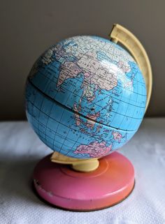 a blue and pink globe sitting on top of a wooden stand