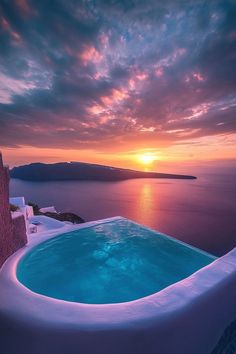 an outdoor swimming pool overlooking the ocean at sunset