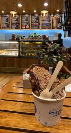 an ice cream sundae with two scoops in it sitting on a wooden table