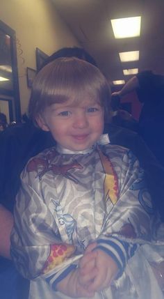 a little boy that is sitting in a chair with his hands on his hips and smiling at the camera