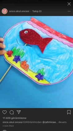 someone is painting a fish in the ocean on a paper plate with toothpicks