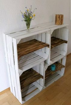 a white shelf with wooden shelves and flowers on top