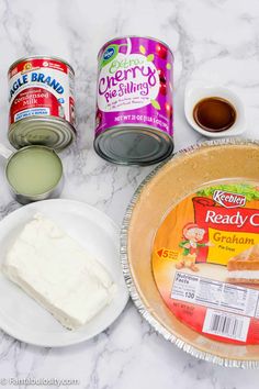 ingredients to make cake sitting on top of a marble countertop, including cream cheese, butter, and yogurt