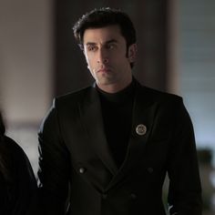 a man in a black suit standing next to a woman wearing a black dress shirt