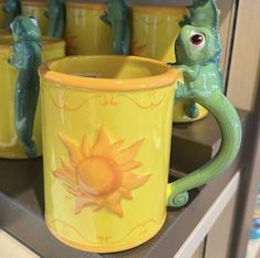 a yellow coffee mug sitting on top of a counter next to other ceramic figurines