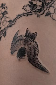 a tattoo on the back of a woman's stomach with an eagle and flowers