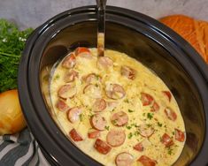 a crock pot with sausage and cheese in it next to carrots, celery