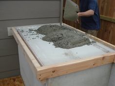 a man standing in front of a building next to a pile of cement on the ground