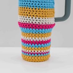 a crocheted coffee cup holder is shown in multi - colored yarn and sits on a white surface