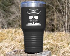 a black tumbler cup sitting on top of a wooden post