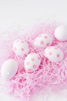 pink and white polka dot eggs in a nest on top of shredded pink material next to an egg box