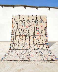 an area rug on the ground in front of a white building with blue sky behind it