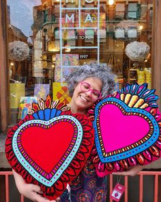 a woman holding two pillows in front of a store window with the words cushions & throws on it