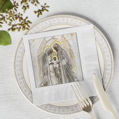 a white plate topped with a silver fork next to a painting on top of it