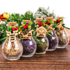 small glass bottles filled with different types of spices and herbs on a table next to christmas decorations