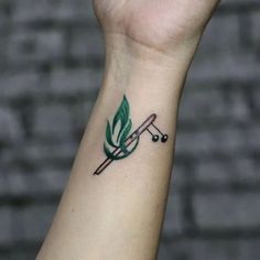 a small green leaf tattoo on the wrist