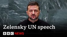 a man standing in front of a microphone with the words zelenskiy un speech