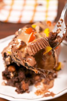 a white plate topped with a piece of chocolate cake covered in candy and frosting