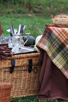 a picnic basket with food and drinks sitting on the grass next to a picnic table