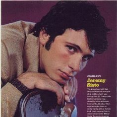 a man with his hand on the back of a chair, posing for a magazine cover