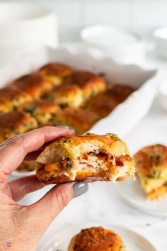 a hand holding a piece of food over a plate