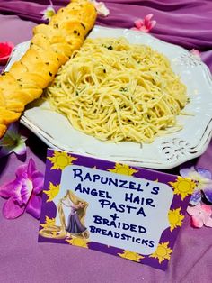 a plate of spaghetti and bread on a purple table cloth next to a sign that says rapunzel's angel hair pasta