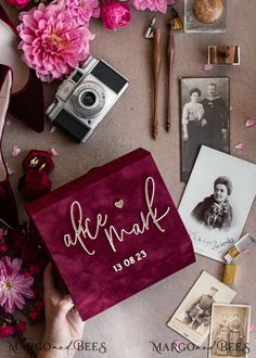 a table topped with lots of pink flowers next to an old fashioned camera and other items