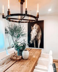 a dining room table with two vases and a horse painting on the wall behind it