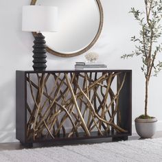 a table with a mirror on it next to a potted plant and a lamp