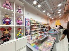 a store filled with lots of toys and people standing in front of the display case