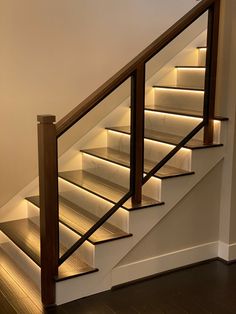 a stair case with lights on the bottom and sides in an empty room next to a wooden floor