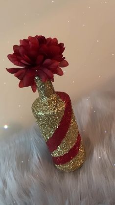 a red and gold vase with a flower in it sitting on some white fur covered ground