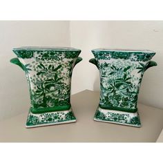 two green and white vases sitting on top of a table