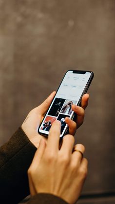 a person holding a cell phone in their left hand and touching the screen with both hands