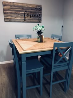 a wooden table with blue chairs and a vase filled with flowers on top of it