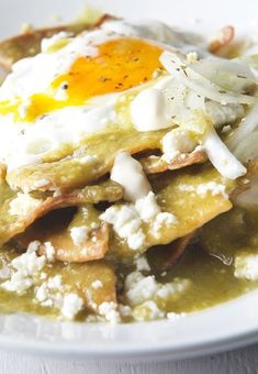 a white plate topped with an egg and cheese enchilada covered in gravy