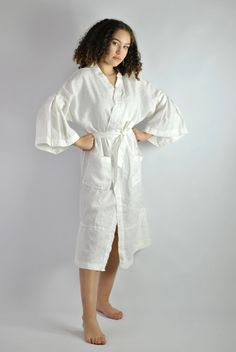 "This is our no. 60 of Conscious Clothing Concept #stayhome This lovely white A-line loose fitting robe is made of pure quality linen. Very modern approach to traditional white spa gown. It has got very flattering wide sleeves that match the bottom of the dress. This unique piece of loungewear can be very versatile. It is great and comfy to wear around the house, hotel or spa. It can be treated as the dress or loose shirt over the shorts for summer look. Perfect for home and the beach. It is the White Wrap Robe For Vacation, White Wrap Dress For Daywear, White Wrap Day Dress, White Long Kimono For Loungewear, White Open Front Daywear Dress, Open Front White Dress For Daywear, White Open Front Dress For Daywear, Long White Robe For Home, Long White Robe For Spring