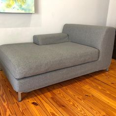 a gray couch sitting on top of a hard wood floor next to a white wall