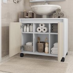 a white sink sitting next to a shelf filled with towels and other bathroom items on top of a rug