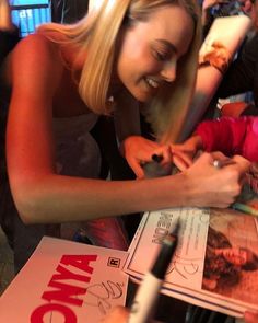 a woman is signing autographs for fans